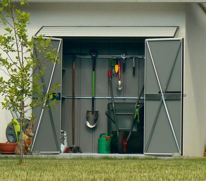 Metalowy domek narzędziowy przy ścianie budynku
