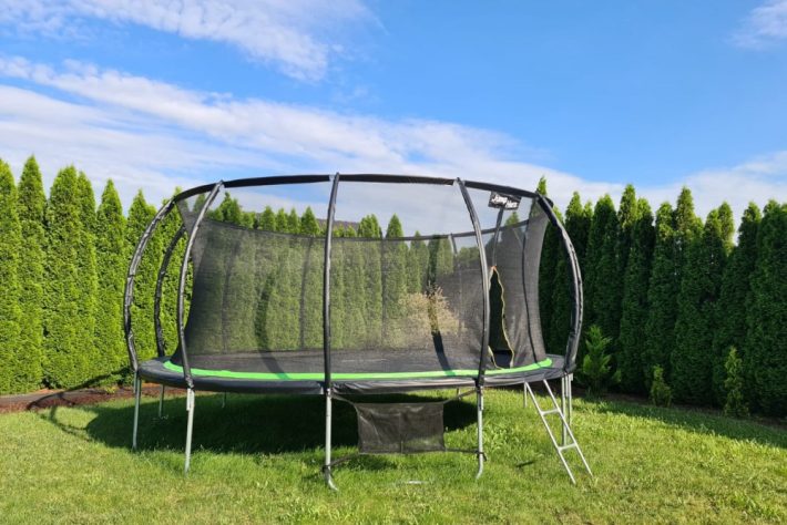 Duża trampolina w zielonym zakątku ogrodu